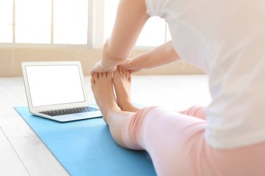Kilitleme sırasında laptoplu genç bir kadın evde yoga yapıyor.