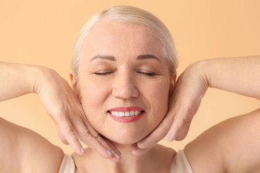 Olgun bir kadın kendine yüz masajı yapıyor.