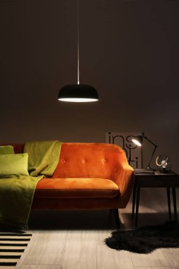 Geceleri oturma odasında ekose ve parlayan lambalar olan şık bir kanepe.