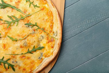 Renkli ahşap arka planda lezzetli peynirli pizza.