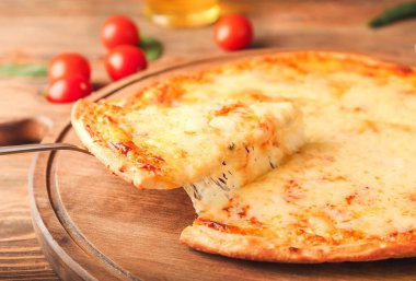 Tahtadan ahşap arka planda lezzetli bir pizza dilimi alıyor.