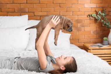 Evde köpek yavrusuyla oynayan tatlı bir kız.