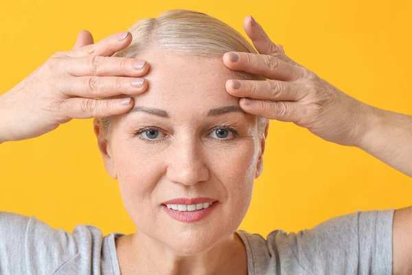 Reife Frau Gibt Sich Gesichtsmassage Auf Farbigem Hintergrund — Stockfoto