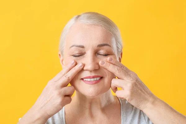 Mujer Madura Dándose Masaje Facial Sobre Fondo Color — Foto de Stock