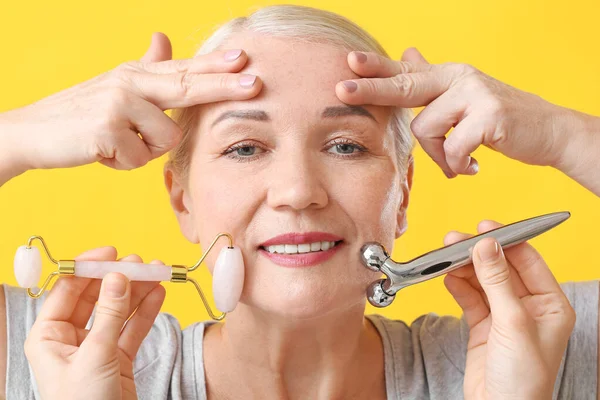 Mujer Madura Con Herramientas Masaje Facial Sobre Fondo Color — Foto de Stock