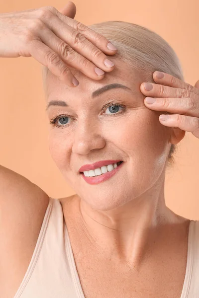 Mujer Madura Dándose Masaje Facial Sobre Fondo Color — Foto de Stock