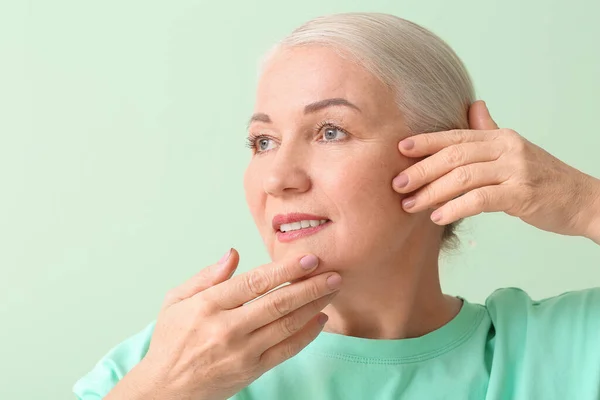 Mature Woman Giving Herself Face Massage Color Background — Stock Photo, Image