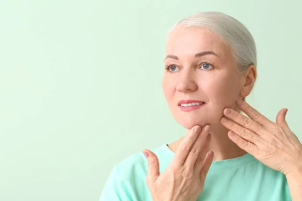 Mujer Madura Dándose Masaje Facial Sobre Fondo Color — Foto de Stock