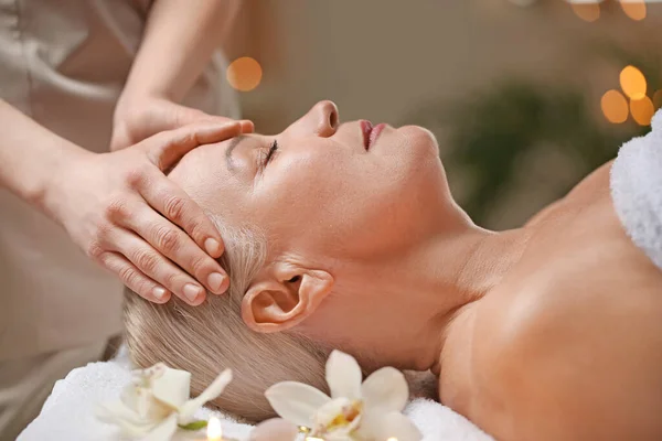 Mature woman receiving face massage in beauty salon