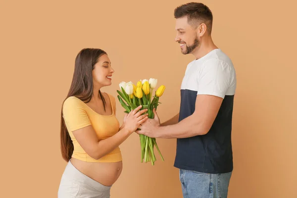 Krásný Těhotný Pár Kyticí Květin Barevném Pozadí — Stock fotografie
