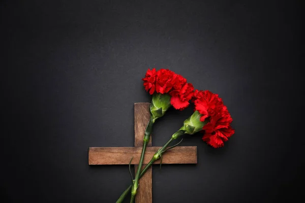 暗い背景に木製の十字架とカーネーションの花 — ストック写真