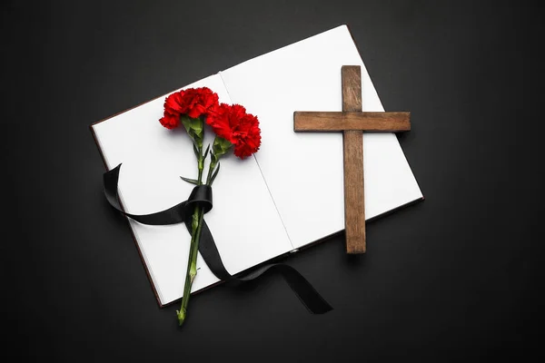 カーネーションの花を持つ本と暗い背景に十字架 — ストック写真