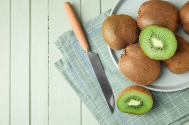 Lezzetli olgun kivi meyvesi ve bıçak renkli ahşap arka planda.