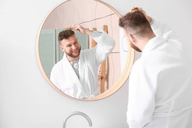 Yakışıklı adam banyoda saçlarını tarıyor.