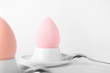 Makyaj süngerleri ve beyaz arka planda kaşıkları olan yumurta tutucuları