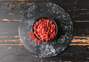 Koyu ahşap arka planda kurumuş goji üzümlü kase.