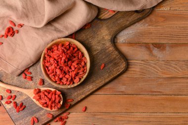 Ahşap arka planda kurumuş kurt üzümlü kase ve kaşık.