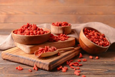 Ahşap arka planda kurumuş kurt üzümlü kase ve kepçe.