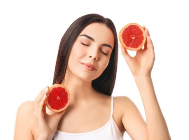 Beyaz arka planda greyfurt olan güzel genç bir kadın.