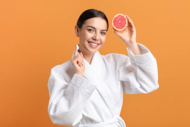 Greyfurtlu güzel bir kadın arka planda yüz kremi sürüyor.