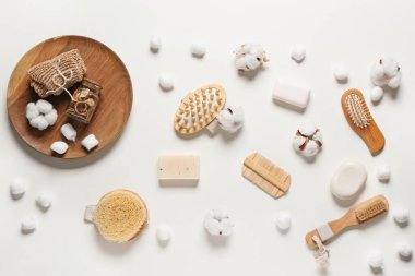 Masaj fırçaları, banyo malzemeleri ve beyaz arka planda pamuk çiçekleri olan kompozisyon