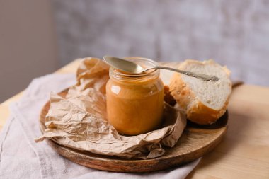 Fıstık ezmeli kavanoz ve tahta masada kaşık.