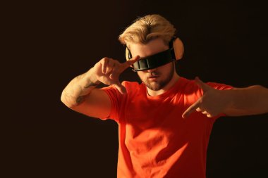 Siyah arka planda kulaklıkları olan yakışıklı genç adamın tonlu portresi.