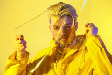 Renkli arka planda plastiği olan yakışıklı bir gencin tonlu portresi.