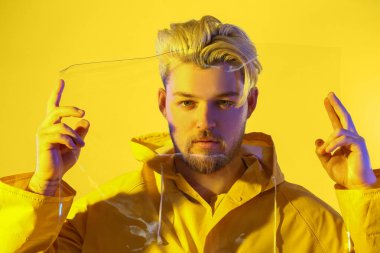 Renkli arka planda plastiği olan yakışıklı bir gencin tonlu portresi.