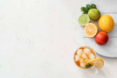 Bir fincan soğuk yeşil çay ve hafif arkaplanda meyveler.