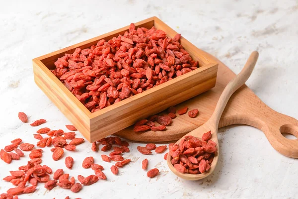 Açık arkaplanda kurutulmuş kurt üzümü dolu kutu ve kaşık.