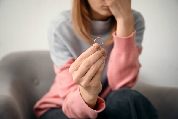 Woman with her wedding ring in room. Concept of divorce