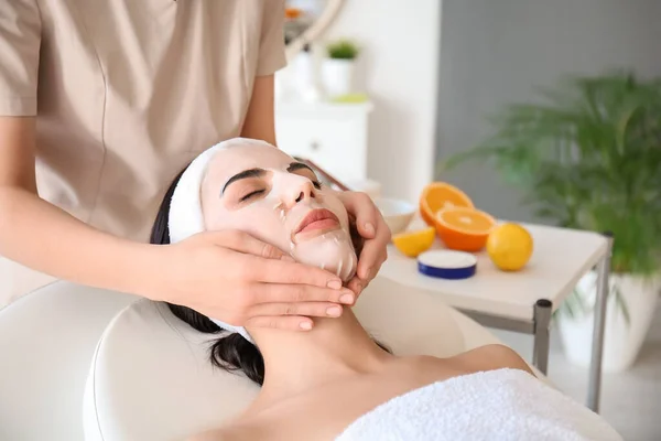 Cosmetologist applying sheet mask on woman\'s face in beauty salon