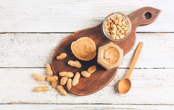 Jar Tasty Peanut Butter Bread Nuts Light Wooden Background — Stock Photo, Image