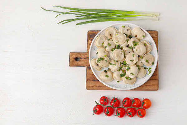 Тарелка с вкусными пельменями на светлом фоне