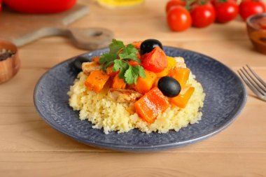 Tahta arka planda kuskus ve sebzeli tabak.