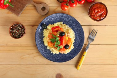 Tahta arka planda kuskus ve sebzeli tabak.