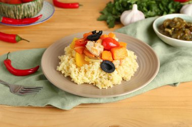 Tahta arka planda kuskus ve sebzeli tabak.