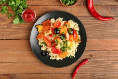 Tahta arka planda kuskus ve sebzeli tabak.