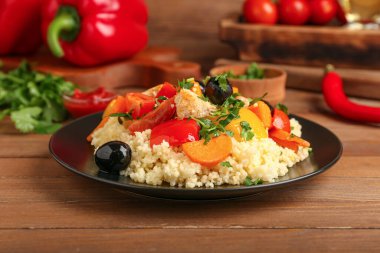 Tahta arka planda kuskus ve sebzeli tabak.