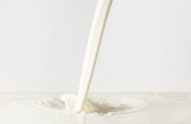 Beyaz zemin üzerine lezzetli süt dökülüyor