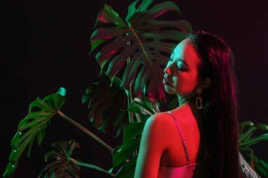 Güzel Asyalı kadın ve koyu arkaplanda tropikal yapraklar