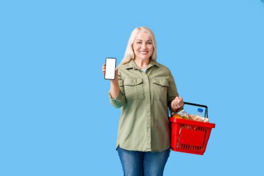 Arkaplanda alışveriş sepeti ve cep telefonu olan olgun bir kadın