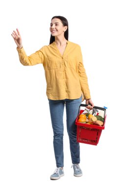 Beyaz arka planda alışveriş sepeti olan genç bir kadın.