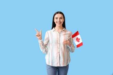 Kanada bayrağıyla güzel genç bir kadın renk arkaplanını işaret ediyor.