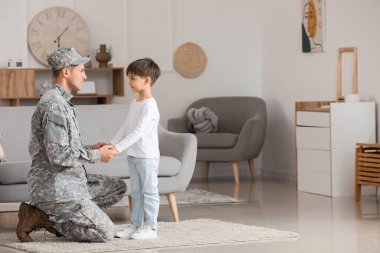 Asker ve küçük oğlu evde el ele tutuşuyorlar.