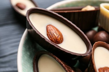 Koyu ahşap arka planda lezzetli çikolata şekerleri olan kase, yakın plan.