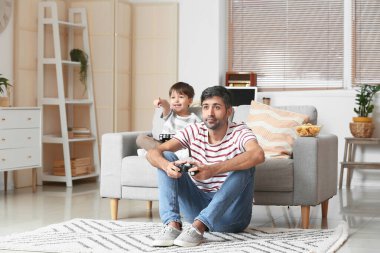 Baba ve küçük oğlu evde video oyunu oynuyorlar.