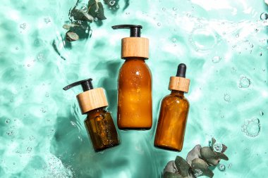 Renkli arka planda suda kozmetik ürünleri ve okaliptüs dalları şişeleri