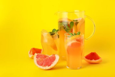 Renkli arka planda gözlük ve bir sürahi lezzetli greyfurt limonatası.